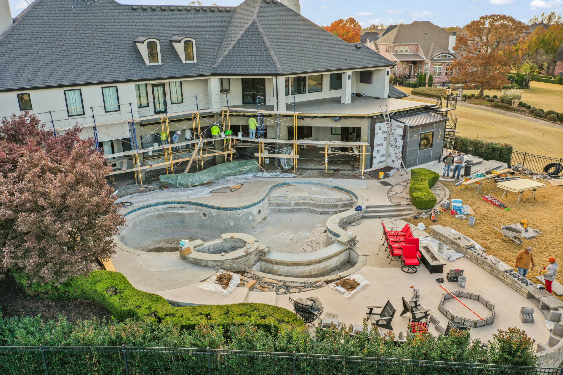 Backyard progress photo showing pool reconstruction, exterior home updates, and construction materials staged around the Shadow Valley property.